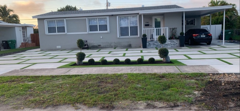 Modern concrete driveway with artificial turf inlay strips by Concrete Designs LLC in Miami-Dade FL
